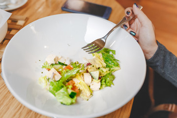 Greek salad in dish with fork on wooden table background