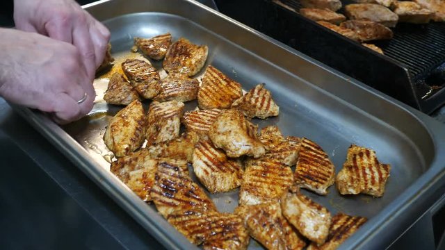 Cooked chicken fillet or turkey chef puts it in a large tray in the restaurant kitchen