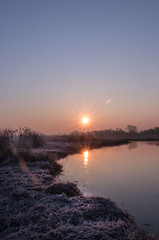 sunrise on the background of a winding wild river, its backwaters and backlit with reed promises, early spring