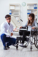 Fototapeta na wymiar Male doctor examining female patient on wheelchair