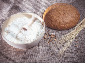  Bunch of wheat ears, a bowl of flour and round bread.