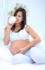 happy pregnant woman drinking milk sitting in the living room.