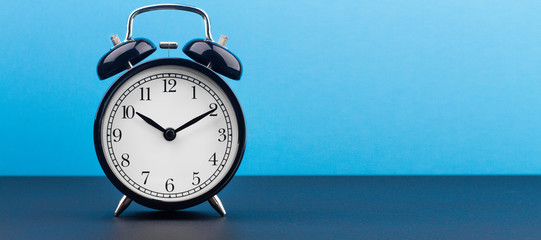 alarm clock on a color background on a wooden board