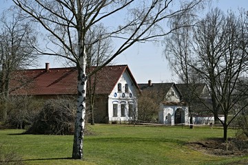 Fototapeta na wymiar Serec, Czech Republic / Europe - April 7 2018: Village square with white decorated houses, birches and green grass on sunny day, blue sky