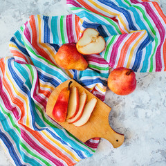 Overhead bright red williams pears on multi color striped textile background.