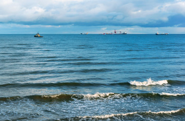 Sea wave, storm at sea. Waves lapping on the shore. Cargo ship at sea.