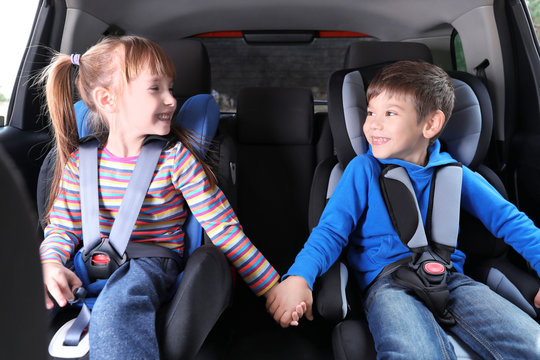 Cute children with fastened seatbelts in car