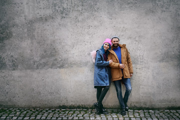 Obraz na płótnie Canvas Young hipster couple near grey wall outdoors