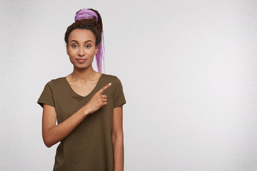 Indoor shot of young african female indicates with finger aside, feels happy and satisfied....