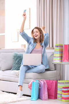 Emotional woman with credit card and laptop at home. Online shopping concept