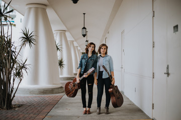 Pretty Female Musicians Walking Down Outdoor Corridor