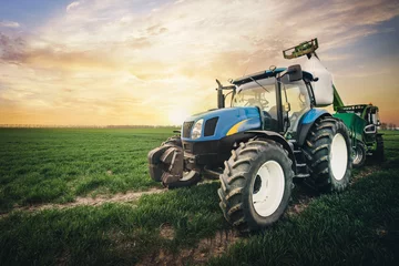 Foto op Plexiglas Tractor een tractor met een zak kunstmest rijdt in het voorjaar over het veld
