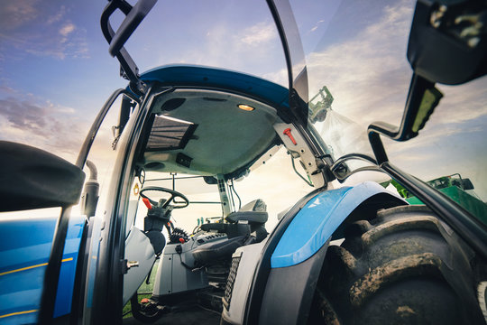 open cab of driver of the tractor stands in the field in the spring