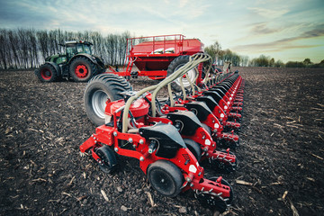 sowing machines stand on the ground in the field in the spring near the tractor
