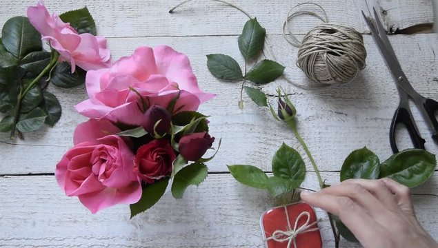 Top view of female decorator leaving a box gift, arranging roses on the wooden table, Concepts - fiorist, occupation, hobby, small business 
