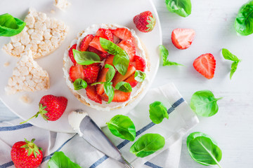 Healthy snack with crisp bread, fresh strawberries, goat cheese, and basil leaves. Easy appetizer recipe.