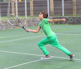 handsome boy in green sports suit, playing tennis