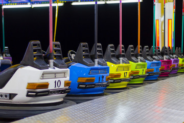 Fototapeta premium A line of colorful, electric bumper cars in autodrom in the fairground attractions at an amusement park.