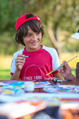 handsome boy in a red baseball cap and cap draws paints