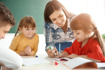 Female teacher helping girl with her task in classroom at school
