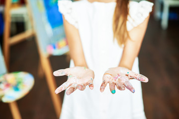 Close up of unrecognizable teenage girl showing hands smudged in paint at camera, copy space