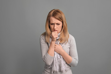 Young woman coughing on color background