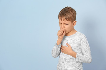 Little boy coughing on light background