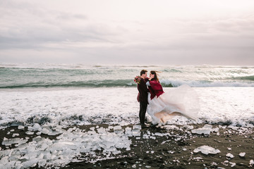 Beautiful Couple is hugging on Black Sand Beach, Iceland. Artwork