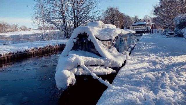 British narrow boat on canal waterway in deep snow during cold winter