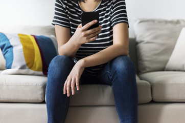 Fototapeta premium Woman using mobile phone on the couch