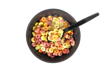 Closeup colorful cereals in bowl with spoon and milk isolated on white background