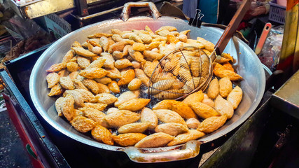 Fish ball being fried in deep pan with boiling oil