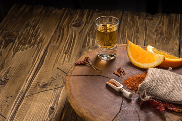 Mezcal - traditional Mexican drink with orange slices, chili papper and worm salt on a old wooden table.