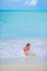 Adorable little girl at beach having a lot of fun in shallow water