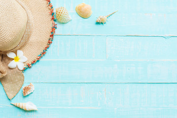 Beach accessories including sunglasses, hat beach, shell and sand on bright blue pastel wooden background for summer holiday and vacation concept.