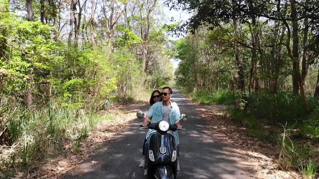 Slow motion Young Couple Riding Motor Scooter Along Country Road