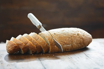 Sliced loaf fresh bread knife wooden table view straight