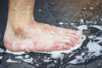 A man's feet are washing, standing on a cement floor.