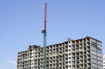 Fototapeta na wymiar Gray new building and red construction crane.