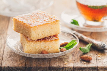 Two slices of homemade semolina cake on a wood vintage rustic table background with mint tea