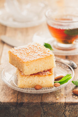 Two slices of homemade semolina cake on a wood vintage rustic table background with mint tea