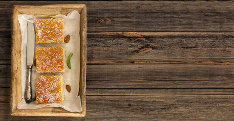 Three slices of homemade semolina cake on a wood vintage rustic table background with mint tea. Overhead or top view composition with copy space