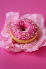 Obraz na płótnie Canvas Donut. pink donut on a light pink crumpled paper on a bright fuchsia background. Appetizing dessert