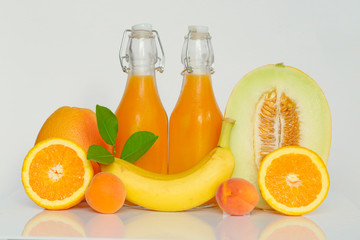 Smoothie. orange multifruit  smoothie in bottles and orange and yellow fruit mix. Healthy smoothie from Grapefruit, banana, orange, apricot, melon in glass bottles on a white background. 