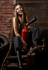 Obraz na płótnie Canvas young woman in a welding glasses holding fire extinguisher. sexy car service worker.