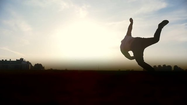 Man Parkour tricker jumper performs amazing flips, silhouette