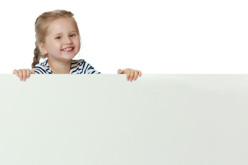 A little girl is looking from behind an empty banner.