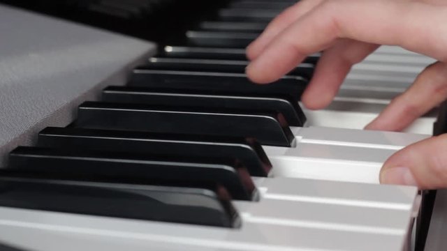 Beautiful fingers on white and black piano keys or a synthesizer play a melody