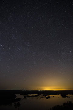 Bright stars of the night sky against the background of the smooth surface of the lake.