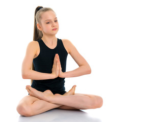 A little girl is meditating in a lotus pose.